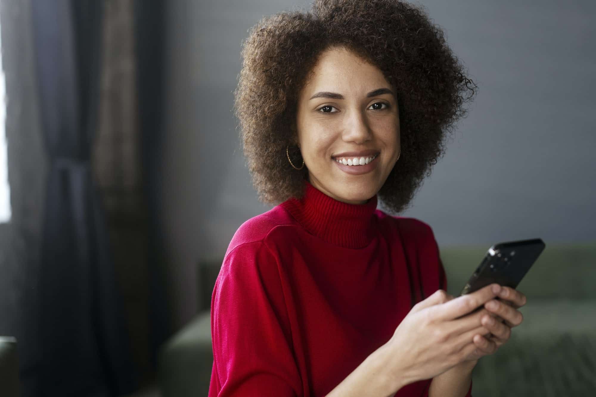 African American Woman In Red Casual Attire Using Mobile Phone Working Online Text Messaging.jpg